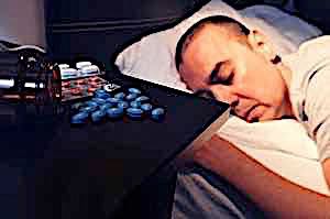 man sleeping with pile of pills next to him