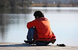 lonely man on dock at lake