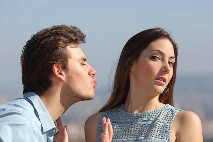 man trying to kiss uninterested woman