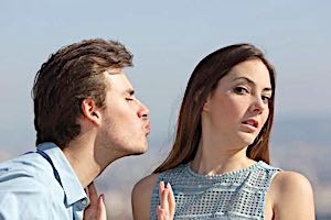 man trying to kiss uninterested woman