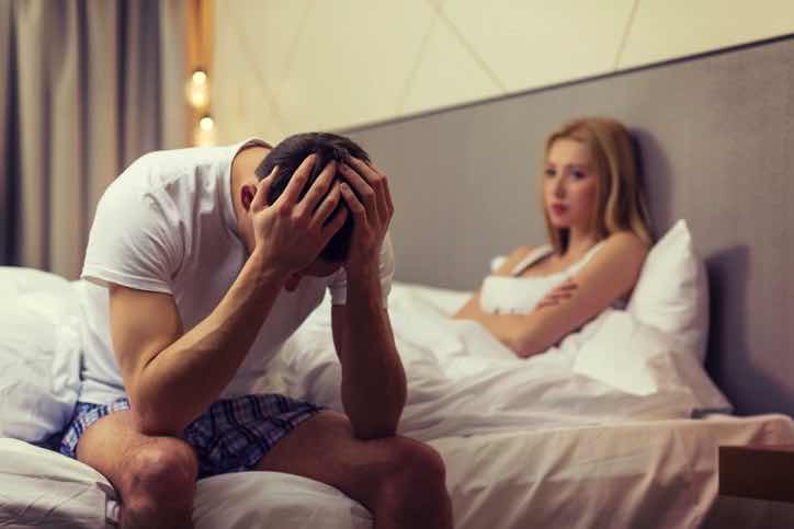 frustrated man in bed next to upset woman