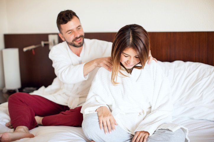 man gives woman massage in bed