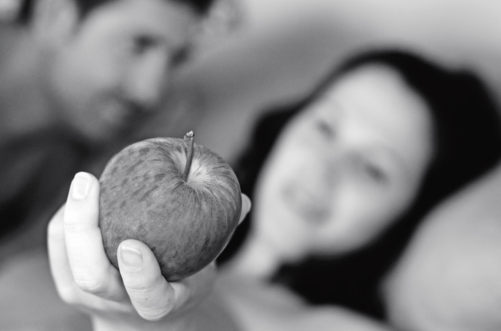 woman tempts man with apple
