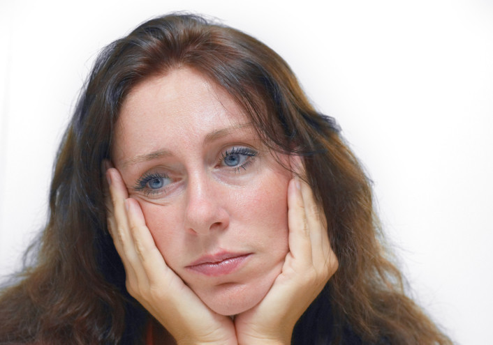 Woman holding face in hands and deep in thought