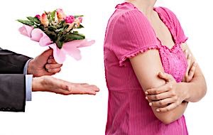 woman turns her back to man trying to apoligize with flowers
