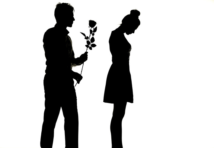 man trying to give flowers to woman who has her back to him