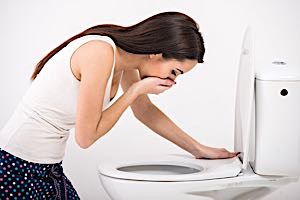 Nauseous woman leaning over toilet