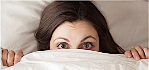 shy woman hiding face under bed sheets