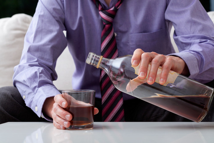 Single man pouring a drink from a half empty bottle