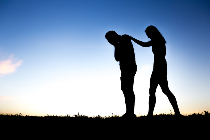 Distraught man comforted by wife